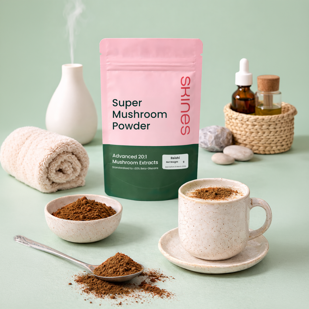 Super Mushroom Powder packaging with a cup of tea, spoonful, and scattered powder on a light green background. | SKINES