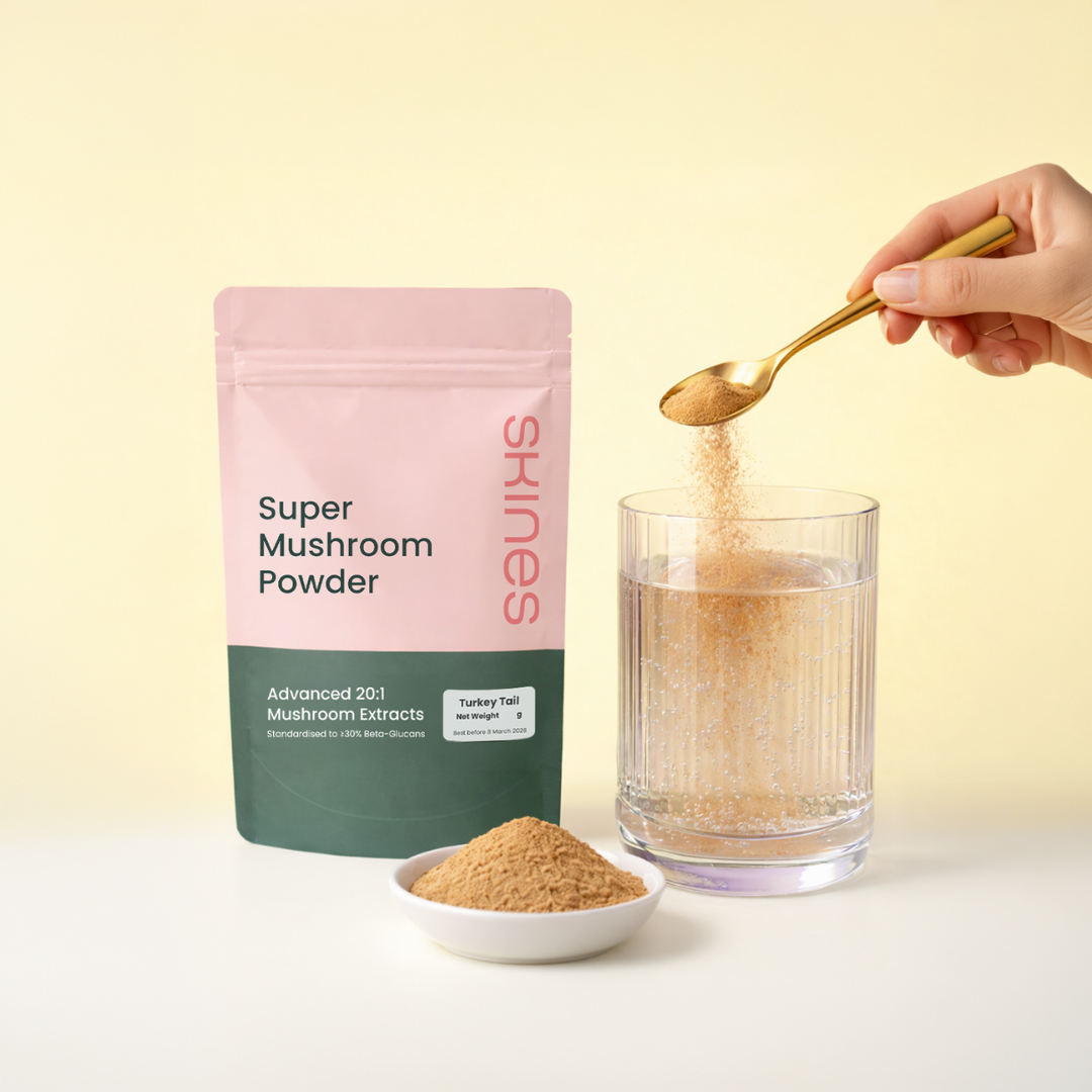 Super Mushroom Powder packaging with a spoonful being added to a glass of water on a light yellow background | SKINES